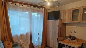 A cozy living area with a sofa, a dining table, and a TV mounted on the wall.