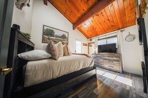 Ein Schlafzimmer mit einem Bett, einem Schminktisch, einem Fernseher und einem Bild an der Wand.