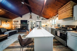 Una cocina moderna con una isla central, electrodomésticos de acero inoxidable y una chimenea.