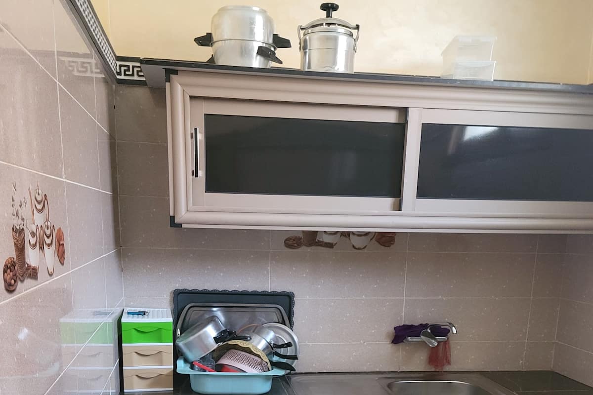 A kitchen with two cabinets, a sink, and a microwave.
