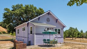 A single-story house with a porch, a green umbrella, and a brick planter. - Fragrance free, 1930 2-bdrm Craftsman farmhouse on 3 acres at the edge of town (Santa Rosa)