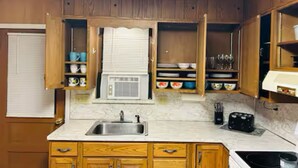 Una cocina con armarios de madera, un fregadero, un microondas y una estufa.
