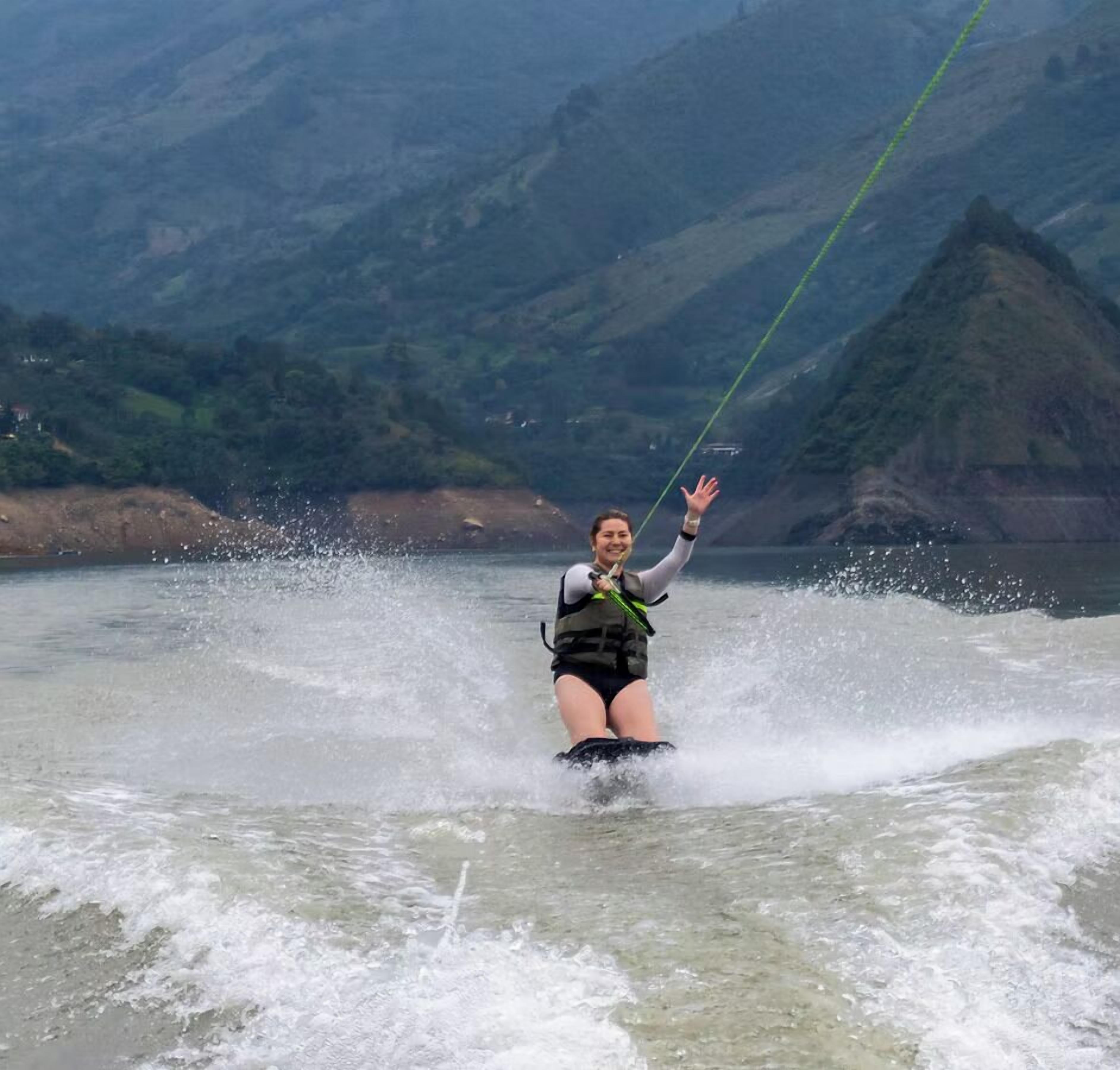 A person water skiing on a river with mountains in the background.