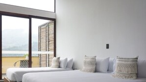 Une chambre moderne avec deux lits, une grande fenêtre et une vue sur l’extérieur.