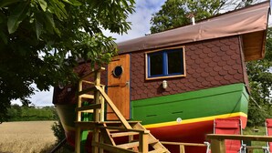 Ein farbenfrohes, bootsförmiges Gebäude mit einer Holztreppe, die zu einem Deck führt.