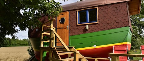 A colorful boat-shaped building with a wooden staircase leading to a deck.