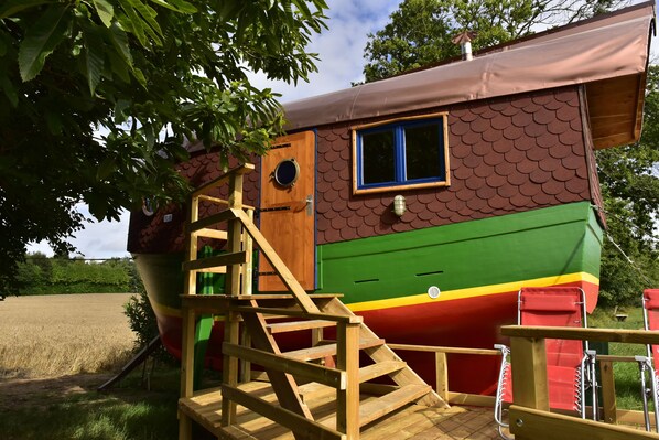 A colorful boat-shaped building with a wooden staircase leading to a deck.