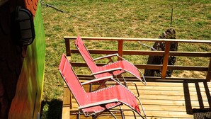 Eine Holzterrasse mit zwei roten Liegestühlen und einem Metallgeländer.