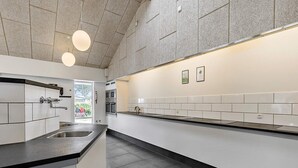 Une cuisine moderne avec des armoires blanches, un plan de travail noir et un grand îlot central. On y trouve deux luminaires suspendus et un évier en acier inoxydable.