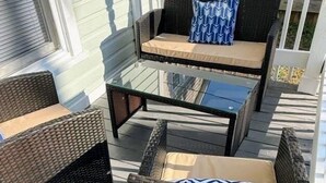 A covered outdoor seating area with wicker furniture and a glass table. - Newly Renovated 2 Bedroom - B (Durham)