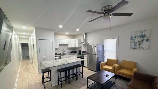 A modern kitchen with white cabinets, a central island, and a ceiling fan. - Newly Renovated 2 Bedroom - B (Durham)