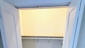 A small, enclosed closet with a wooden floor and a light-colored wall. - Newly Renovated 2 Bedroom - B (Durham)