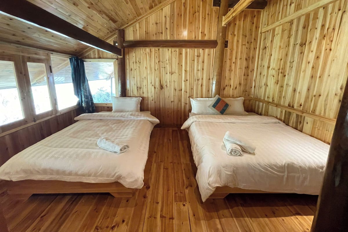Une pièce de cabane en bois avec deux lits, une fenêtre et un plafond en bois.