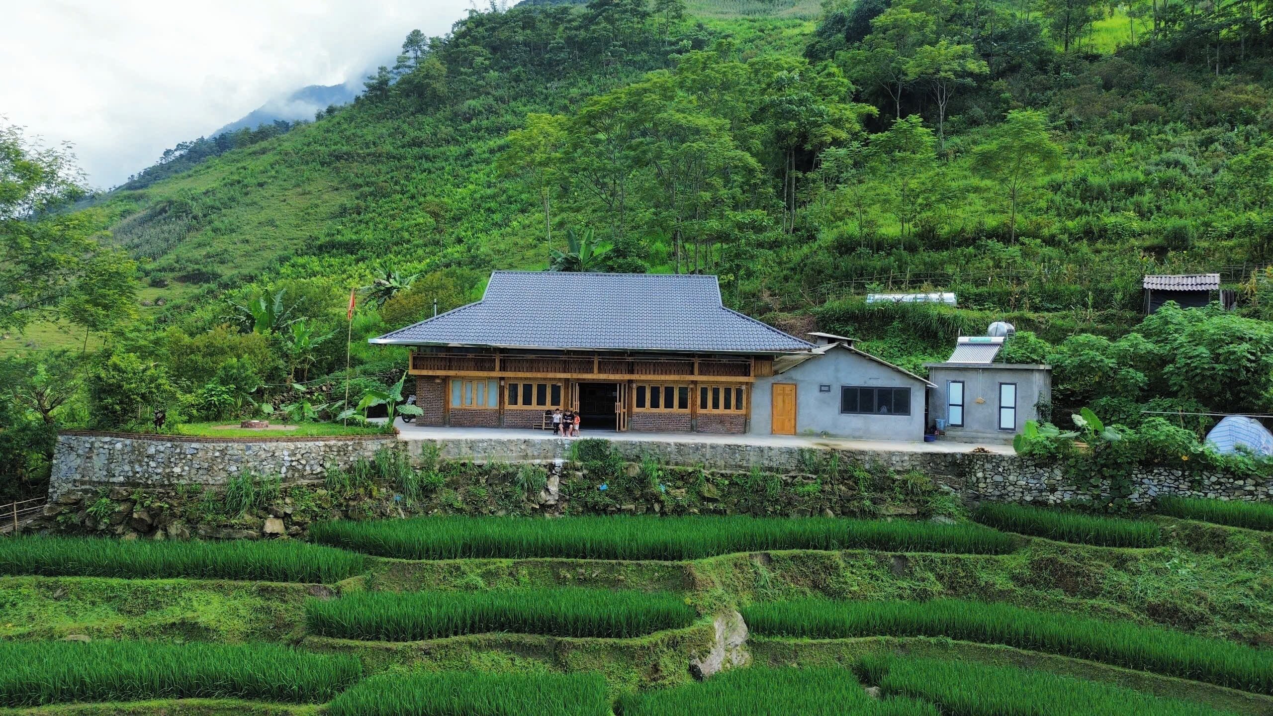 A traditional building with a tiled roof, surrounded by lush green terraced fields.