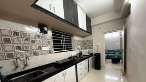A kitchen with white cabinets, black countertops, and patterned backsplash tiles.