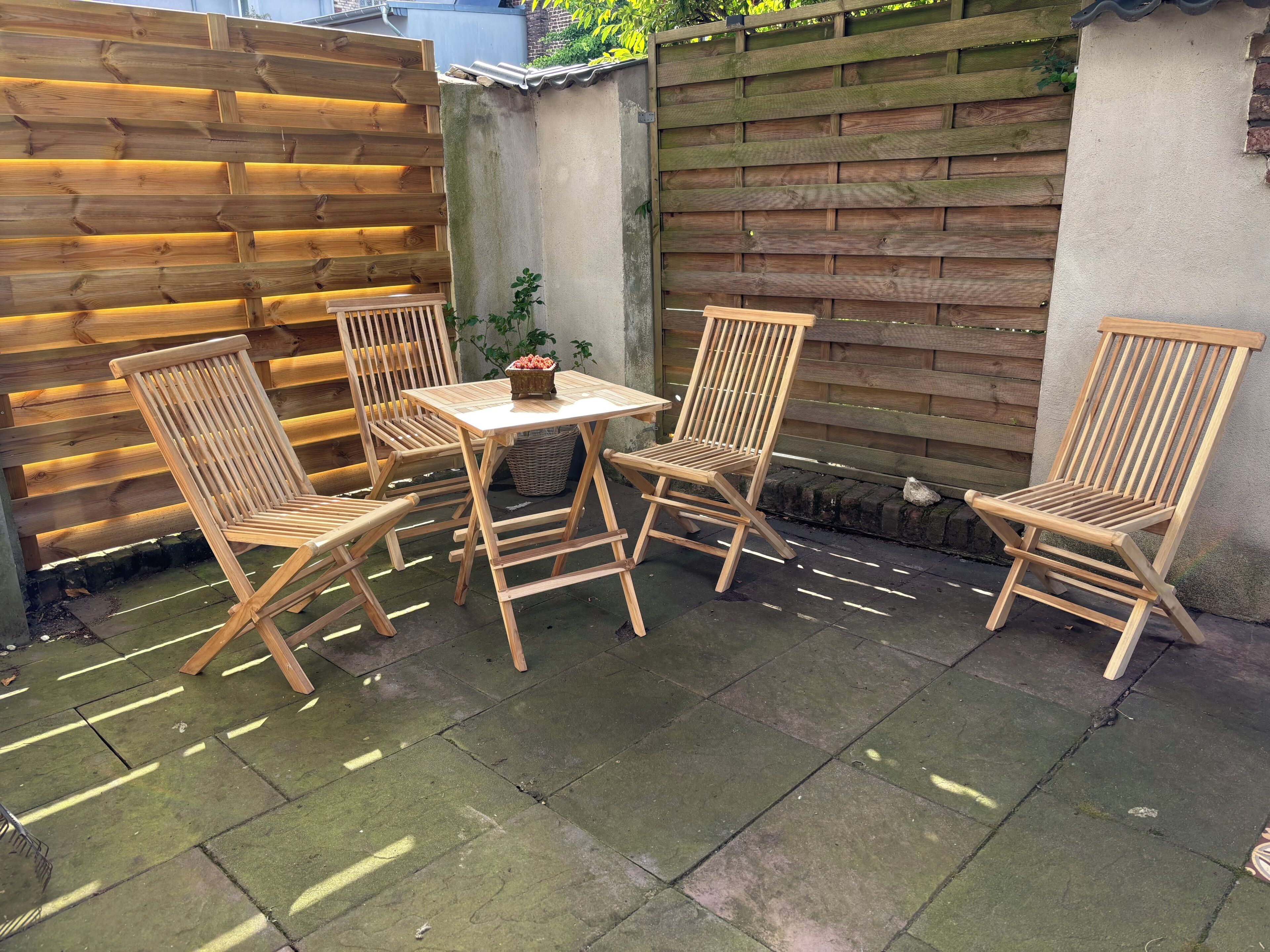 A wooden outdoor seating area with a table and four chairs, a wicker basket, and a small plant.
