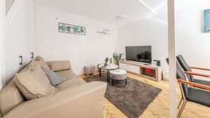 A modern living room with a sofa, a coffee table, a TV, and a chair.