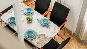 A dining table with teal plates and a small potted plant, surrounded by black chairs with wooden armrests.