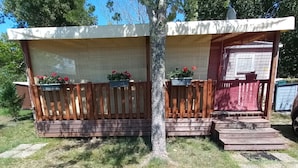 Two wooden structures with attached porches, each with a small garden bed.