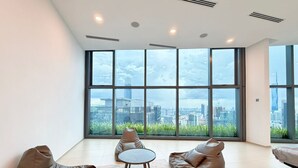 Een moderne woonkamer met grote ramen, een ronde salontafel en twee relaxfauteuils.