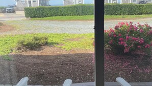 Vista desde una ventana sobre una zona residencial con casas, un seto y un camino de grava.