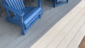 Un porche cubierto con dos sillas Adirondack azules y una mesita.