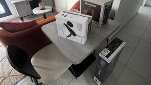 Un salon moderne avec un canapé gris, une table basse ronde et une machine à café Nespresso.