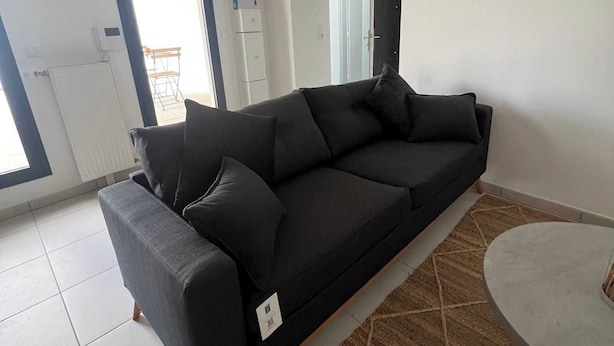 Un salon moderne avec un canapé gris foncé, une table basse ronde et un tapis à motifs.
