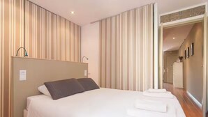 A hotel room with a large bed, striped curtains, and a neatly made bed with towels. - Nice apartment in Gracia neighborhood (Barcelona)