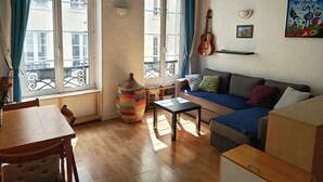 A cozy living room with a wooden floor, a sofa, a table, and a colorful woven basket. - Cosy studio in the heart of Paris (Paris)