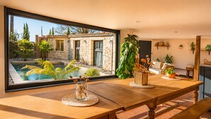 A wooden dining table with a view of a stone house and a swimming pool. - Maison Azur - Pool - Private cinema - 15 min Saumur (Doué-en-Anjou)