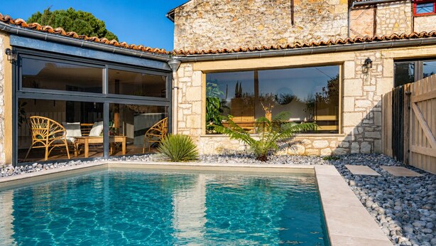 A pool with clear water, surrounded by stone walls and a wooden deck. - Maison Azur - Pool - Private cinema - 15 min Saumur (Doué-en-Anjou)