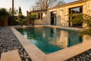 A swimming pool with a stone wall and a wooden deck.