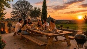 A group of people dining outdoors at a wooden table with a barbecue grill nearby. - Maison Azur - Pool - Private cinema - 15 min Saumur (Doué-en-Anjou)