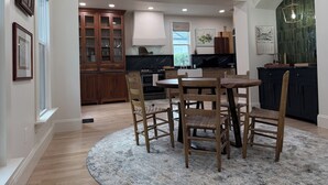 A modern kitchen with wooden cabinets, a dining area with a round rug, and a chandelier. - 3BR Luxury Oregon District Stay - Walk to Breweries, Dining + Free Parking (Dayton)