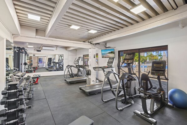 Une salle de sport équipée de tapis de course, de vélos elliptiques et de poids libres.