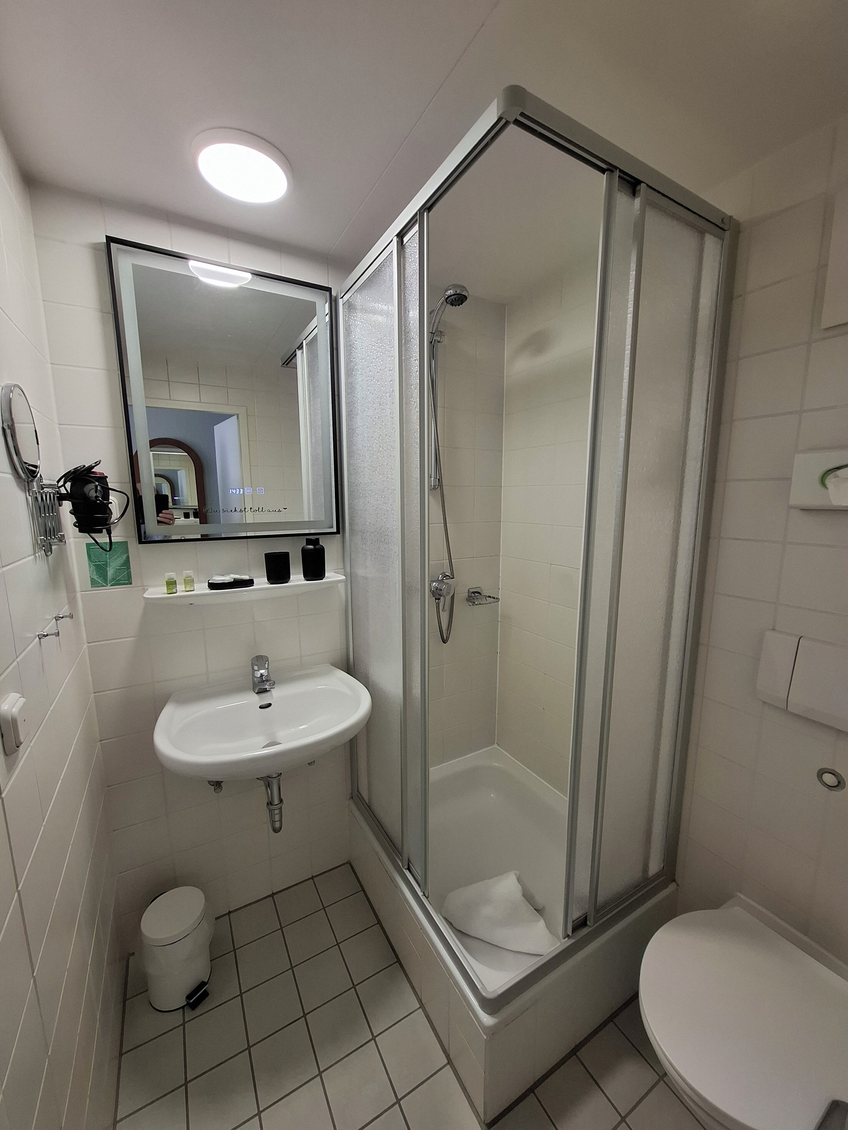 A modern bathroom with a glass-enclosed shower, a white sink, and a toilet.