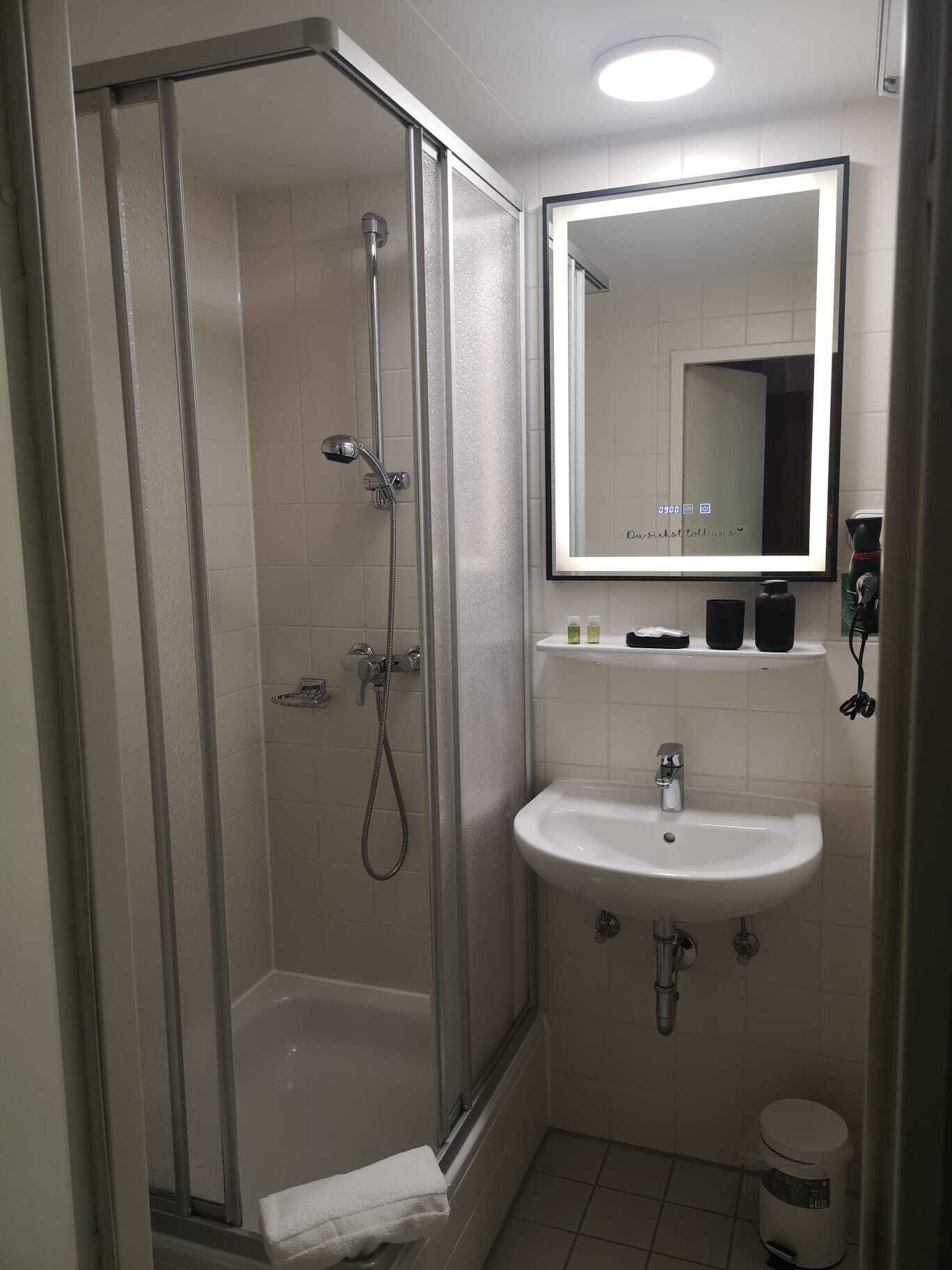 A modern bathroom with a glass-enclosed shower, a white sink, and a mirror above the sink.