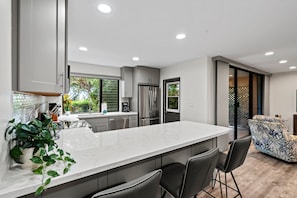 Una cocina moderna con una isla grande, electrodomésticos de acero inoxidable y vistas al exterior.