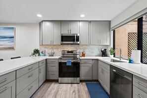 Una cocina moderna con armarios grises, electrodomésticos de acero inoxidable y un salpicadero de azulejos.