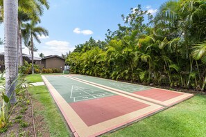 Ein Shuffleboard-Spielfeld, umgeben von üppigem Grün und Palmen.