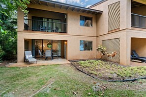 Ein modernes, zweistöckiges Gebäude mit einer überdachten Terrasse, Sitzgelegenheiten im Freien und einem angelegten Garten.