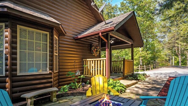 Eine Blockhütte mit Veranda, Sitzgelegenheit im Freien und einem Feuerkorb.