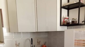 A kitchen with white cabinets, a granite countertop, a stainless steel sink, and a refrigerator.