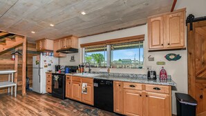 A kitchen with wooden cabinets, a dishwasher, a sink, and a window with a view of the outside.