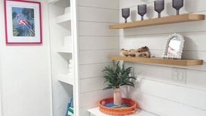 Een witte kamer met houten planken, een witte kast en een lijst met een flamingo.