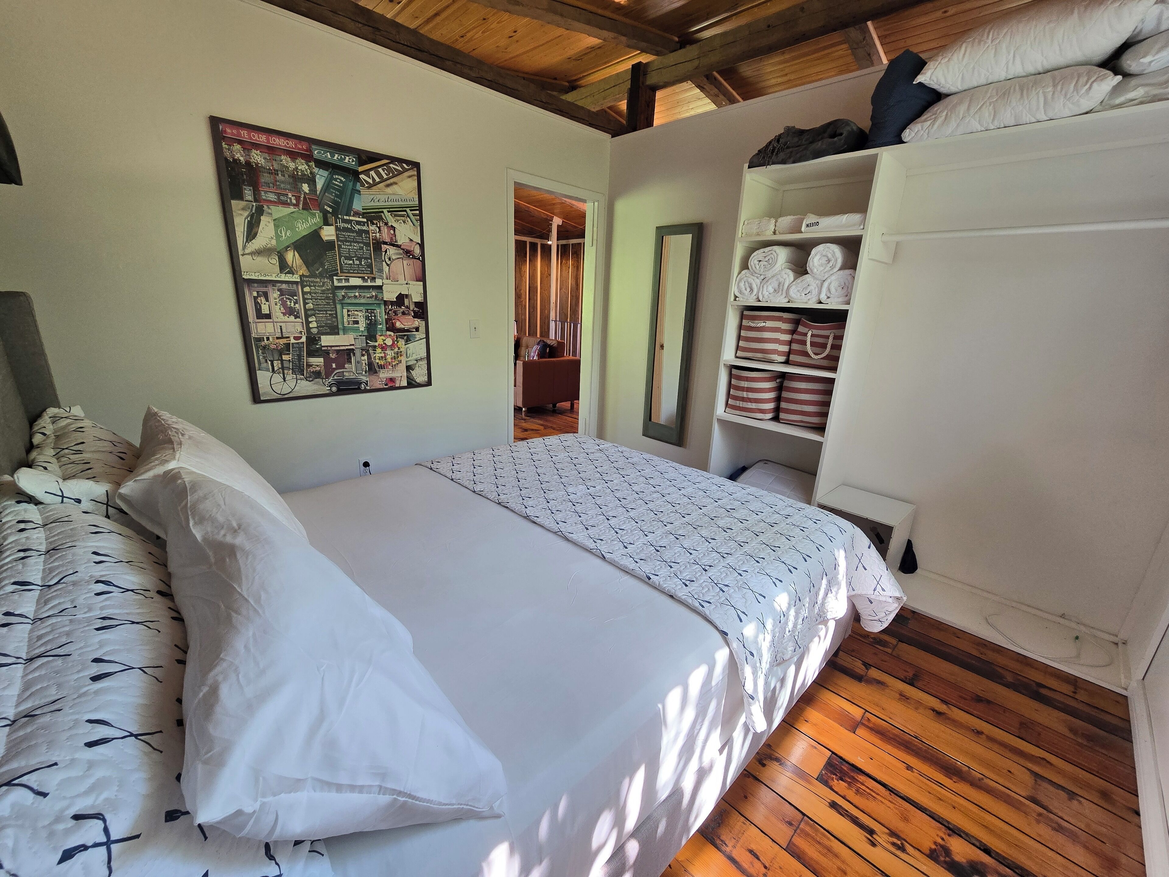 A bedroom with a bed, a wardrobe, a poster on the wall, and a wooden ceiling.
