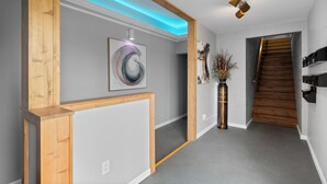 A hallway with a wooden frame, a gray wall, a staircase, and a modern light fixture. - Central Festus Studio Apartment. Private Parking-Gigabit Wifi-Full Size Kitchen. (Festus)