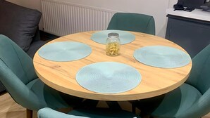 A round wooden table with four light blue placemats and a glass jar with a metal lid. - Cosy 3-Bed Home in Central Colchester (Colchester)