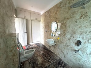 A bathroom with a marble floor, a toilet, a sink, and a shower.